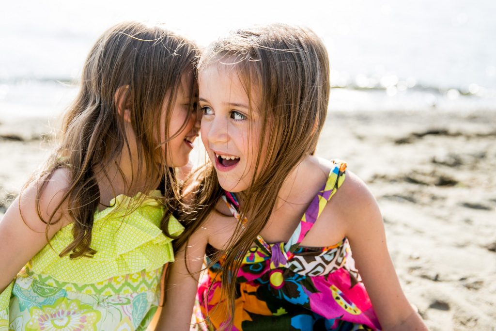 Victoria BC Family Photographer | sisters whisper to each other on the beach - contact us